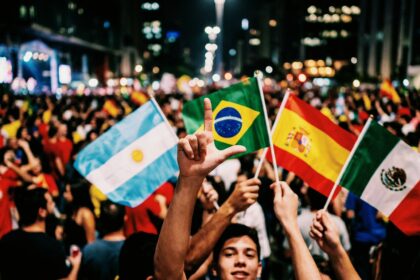Imagem ilustrativa de uma multidão fazendo o L com bandeiras do Brasil, Espanha, México e Argentina (Créditos: Adamy Gianinni)